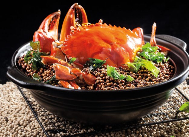 Granchio gigante saltato con pepe bianco e pasta di riso servito in un tegame di argilla - una ricetta di chef Daniel Cheung