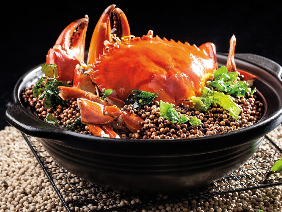 Granchio gigante saltato con pepe bianco e pasta di riso servito in un tegame di argilla - una ricetta di chef Daniel Cheung