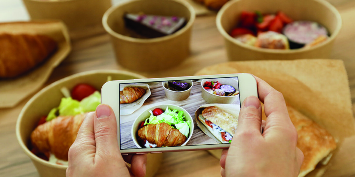 Female food blogger reviewing takeout food, taking video on phone. Italian sub sandwich, french croissant w/ salmon, chocolate cheesecake. Close up, top view, pov, copy space, wooden table background. Female food blogger reviewing takeout food, taking video on phone. Italian sub sandwich, french croissant w/ salmon, chocolate cheesecake. Close up, top view, pov, copy space, wooden table background.