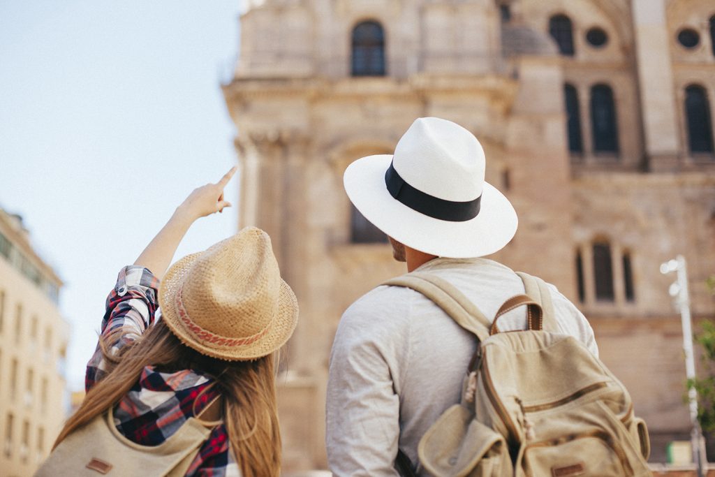 I turisti stranieri tornano a prenotare le vacanze in Italia. Nella foto, due turisti di spalle che indicano un monumento storico italiano.