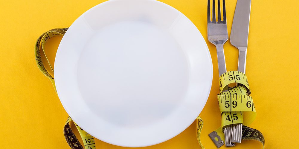 Cucina sartoriale: un piatto vuoto accanto ad un metro da sarto. Immagine per l'editoriale di Elsa Mazzolini sulla cucina sartoriale