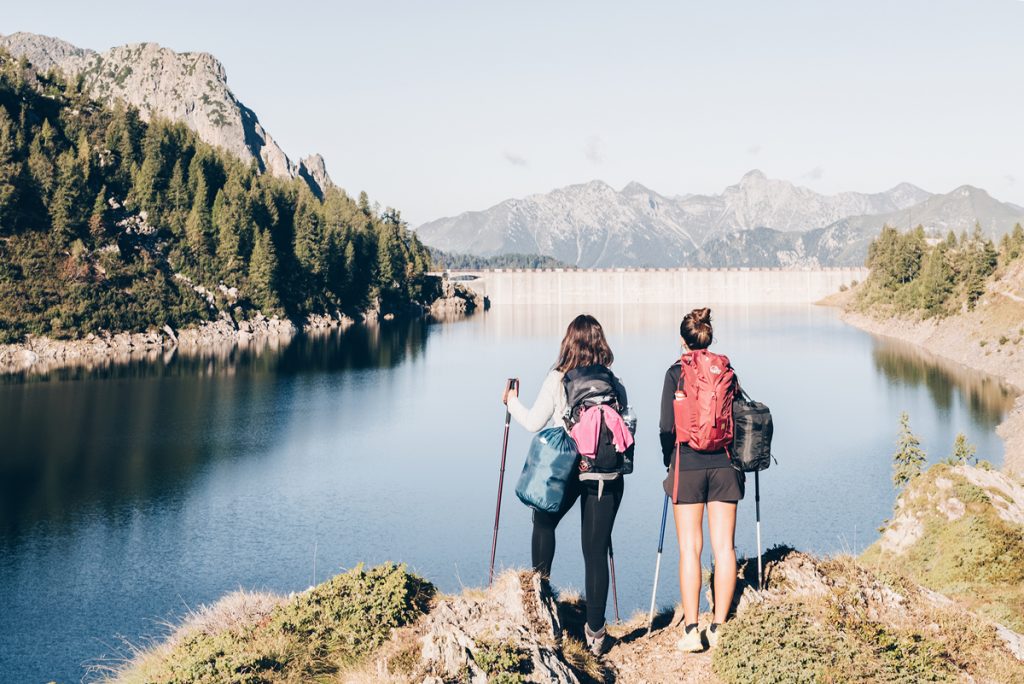 Viaggi sostenibili, escursioniste con vista lago e montagne