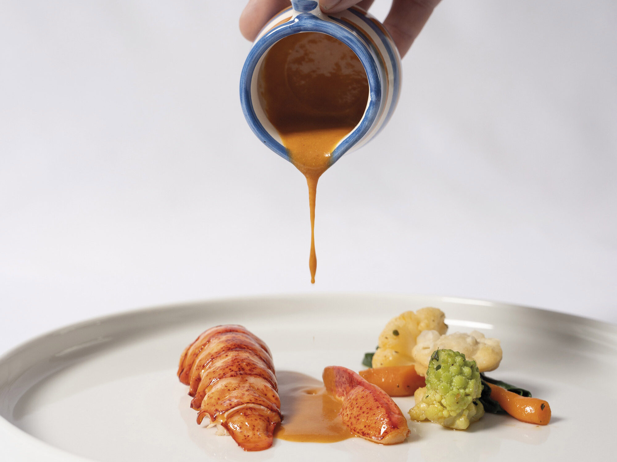 Astice con composé di verdurine baby stagionali, salsa royale e raviolo di foie gras