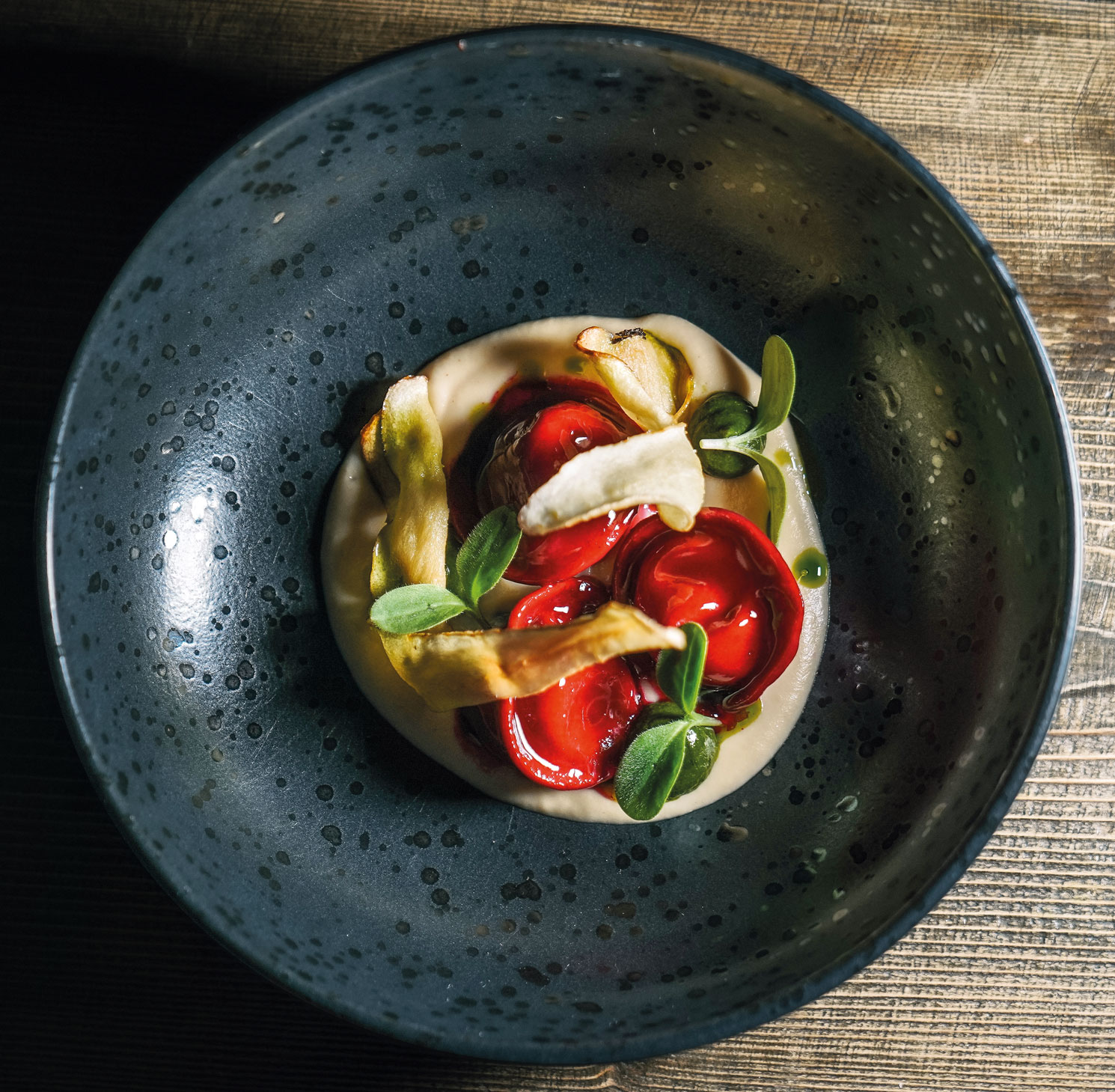 Ravioli di barbabietola rossa con cuore di formaggio, serviti con chips di radice di prezzemolo